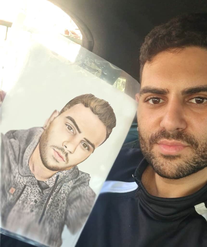 לקוח מחזיק ציור דיוקן של עצמו בעפרונות צבעוניים