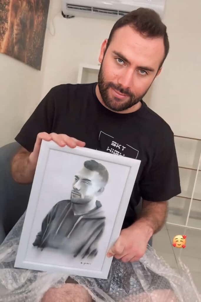 לקוח מחזיק ציור דיוקן של עצמו בעפרונות צבעוניים